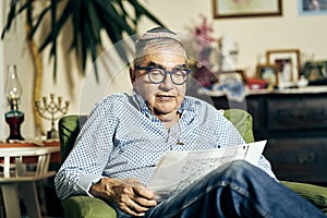 Jewish senior with glasses in the armchair reading a torah book