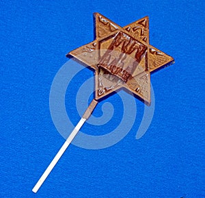 Jewish Star of David dark chocolate candy pop on white stick during Hanukkah