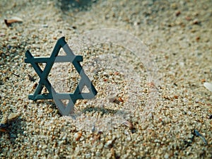 Jewish star like piece of plastic waste in the sand of the sea beach