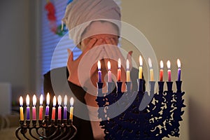 Jewish woman blessing on colourful candles on candelabrum on the eight day of Hanukkah Jewish holiday festival