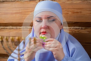 A Jewish woman with her head covered in blue at the Pesach Seder table eats matzo and maror