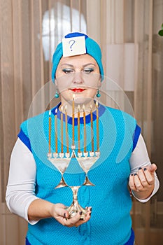 A Jewish woman in a kisui rosh headdress with a Hanukkah candlestick with burning candles in her hands mentally asks a