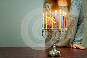 Jewish Woman lighting Hanukkah Candles in a menorah.