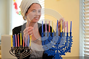 Jewish woman placing colorful candles on candelabrum