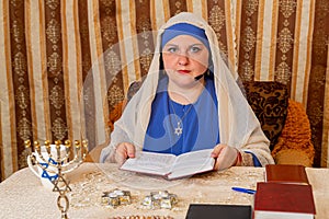 A Jewish woman from the Progressive Judaism community prays in a tallit at a table