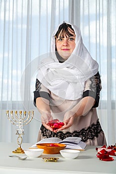 A Jewish woman in a white headscarf performs superstitious conspiracies before the wedding with rose petals to be the