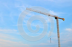 Jib construction tower crane at a construction site on the blue sky background