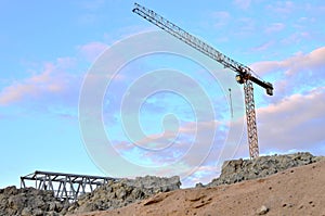 Jib construction tower crane and new residential buildings at a construction site on the sunset and blue sky background