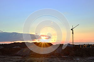 Jib construction tower crane and new residential buildings at a construction site on the sunset and blue sky background