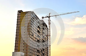 Jib construction tower crane and new residential buildings at a construction site on the sunset and blue sky background