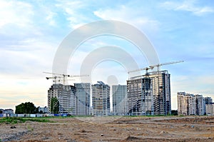 Jib construction tower crane and new residential buildings at a construction site on the sunset and blue sky background