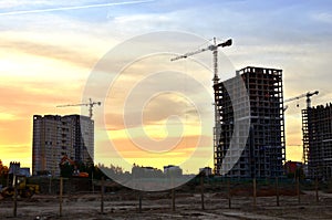 Jib construction tower crane and new residential buildings at a construction site on the sunset and blue sky background