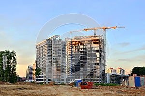 Jib construction tower crane and new residential buildings at a construction site on the sunset and blue sky background