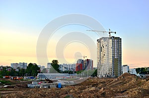 Jib construction tower crane and new residential buildings at a construction site on the sunset and blue sky background