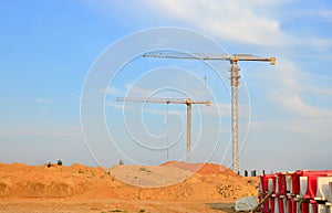 Jib construction tower cranes at a construction site on the blue sky background