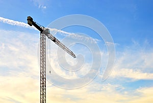 Jib tower crane at a construction site on the blue sky background