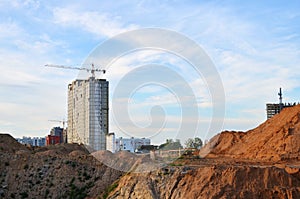 Jib tower crane and new residential buildings at a construction site on the blue sky background