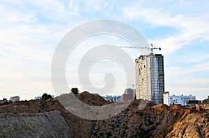 Jib tower crane and new residential buildings at a construction site on the blue sky background