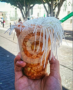 Jicama in a cup called bomba that contains chilli powder, lime, cheese, onion and vinegar and is a traditional street food in the