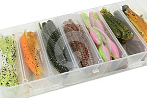 Jig silicone fishing lures in plastic tackle lure box. Silicone fishing baits isolated. Colorful baits. Fishing spinning bait.