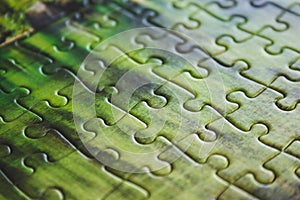 Jigsaw puzzle. Closeup of green jigsaw puzzle peices. Conceptual photo with focus on completed puzzle