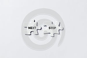 Jigsaw puzzle pieces with the message next step. To decide for the direction of action in business, education or life