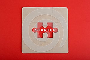 Jigsaw Puzzle Pieces with word & x22;Startup& x22; on red background