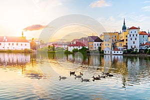 Jindrichuv Hradec cityscape at sunset time reflected in the Little Vajgar pond with flock of ducks, Czech Republic