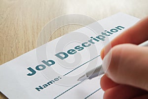 Job Description with Hand and Pen on the table.