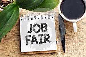 JOB FAIR text written in an office notebook on a wooden table. Business concept