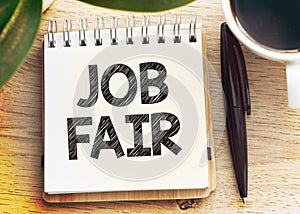 JOB FAIR text written in an office notebook on a wooden table. Business concept