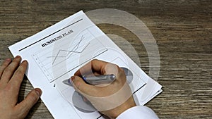 Job with finances in the office on a laptop,the employee holds paper with the inscription business plan.Businessma.market research