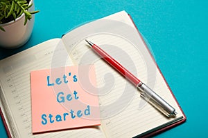 Job interview concept . Office table top view. Notepad, pen and reminder with word Let's Get Started