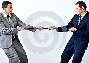 The job market is really harsh at the moment. Two businessmen involved in a tug-of-war while wearing suits and isolated