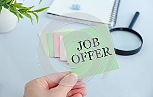 JOB OFFER text on a notebook in the hands of a girl sitting at a table