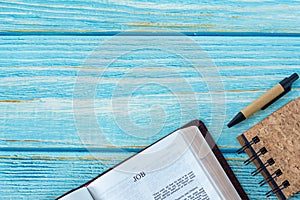 Job open Holy Bible Book on a rustic wooden background with a notebook and pen