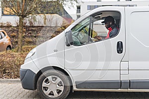 Job - postal delivery person. Outdoor view of a half of white delivery truck and focused Black male courier sitting
