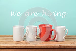 Job recruit concept with coffee cups and text `We are hiring`. Business background