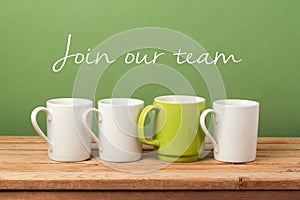 Job recruit concept with coffee cups and text `Join our team`. Business background photo