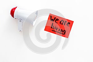 Job recruiting advertisement. We are hiring lettering near megaphone on white background top view copy space