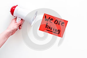 Job recruiting advertisement. We are hiring lettering near megaphone on white background top view copy space