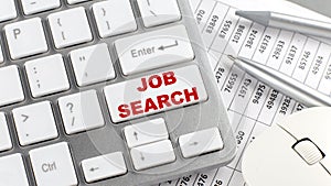 JOB SEARCH text on a keyboard wirh chart and pencil