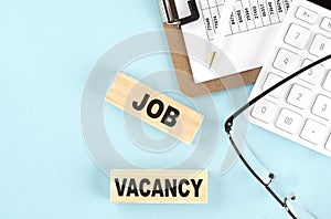 JOB VACANCY text written on wooden block with clipboard,eye glasses and calculator Business concept