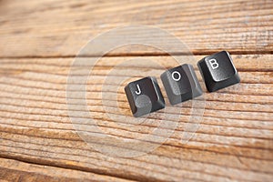`JOB` wrote with keyboard keys on wooden background