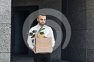 Jobless male worker moving out office with box full of personal belongings, lost job and left without money, copy space