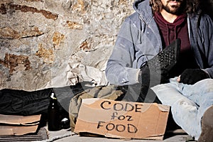 Jobless man sits with keyboard and cardboard sign