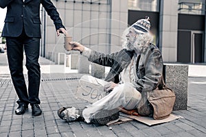 Jobless miserable man sitting on the street in dirty rugs