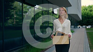 Jobless woman who has just been released and going near the business centre, holding a box containing work items