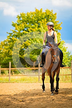 Jockey girl doing horse riding on countryside meadow