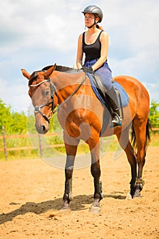 Jockey girl doing horse riding on countryside meadow